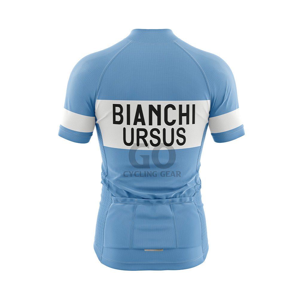 Back view of a light blue short-sleeved cycling jersey. A wide white horizontal band across the upper back features "BIANCHI" in large black capitalized letters, with "URSUS" in black capitalized letters directly below it. Three pockets are visible on the lower back, and the sleeves display white bands with "BIANCHI" in black text.