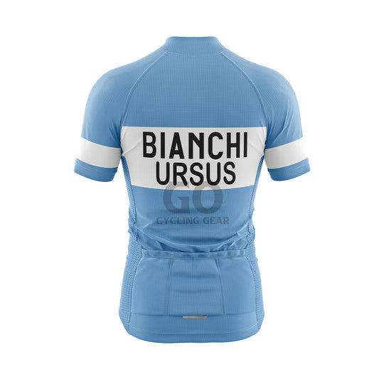 Back view of a light blue short-sleeved cycling jersey. A wide white horizontal band across the upper back features "BIANCHI" in large black capitalized letters, with "URSUS" in black capitalized letters directly below it. Three pockets are visible on the lower back, and the sleeves display white bands with "BIANCHI" in black text.