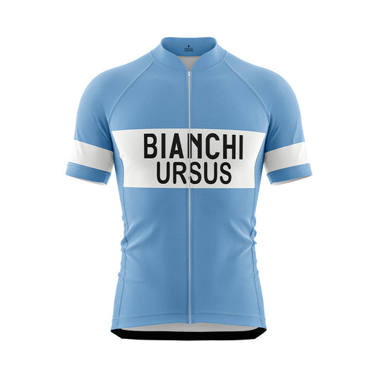Front view of a light blue short-sleeved cycling jersey with a full-length zipper. A wide white horizontal band across the chest features "BIANCHI" in large black capitalized letters, with "URSUS" in black capitalized letters directly below it. The sleeves have white bands with "BIANCHI" in black text.
